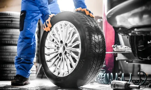 Technician fitting a new tyre on a car